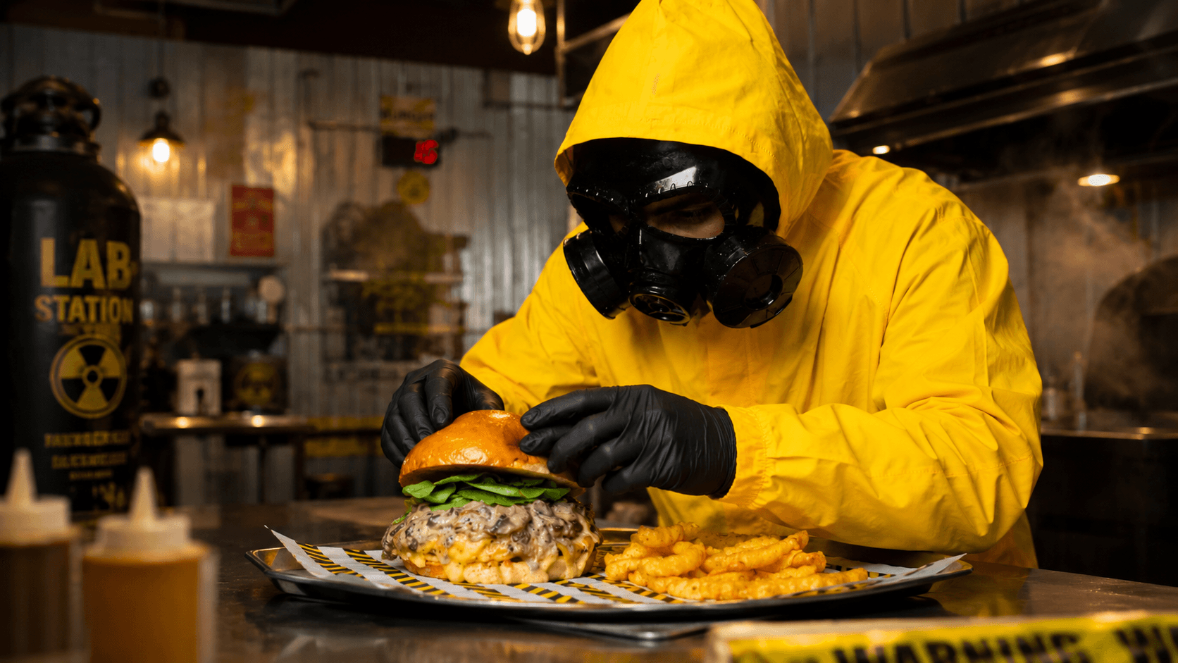 Lab Station team member in yellow protective suit presenting a loaded burger